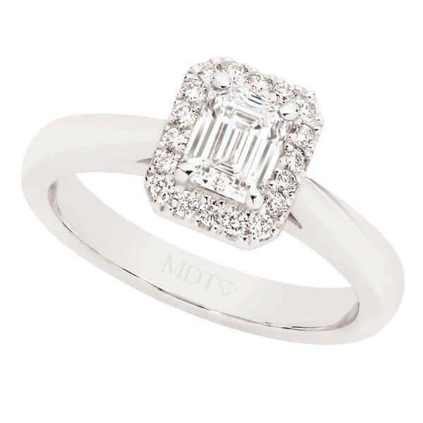 An Emerald Cut Diamond Halo Engagement Ring C1067 is a stunning piece of jewelry that elegantly combines the brilliance of an emerald cut diamond with the enchanting beauty of a halo setting. This exquisite ring is