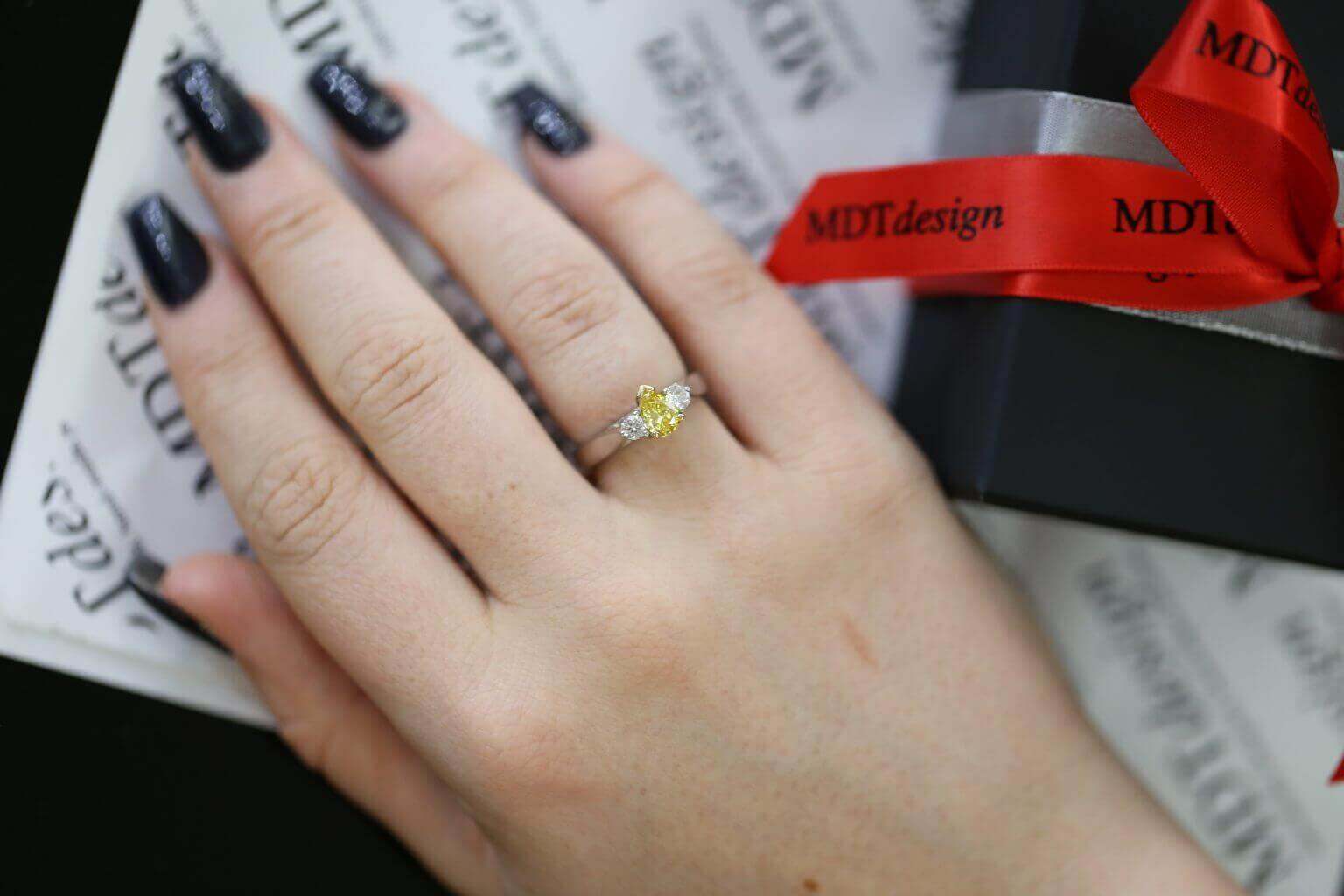 A woman's hand holding a Fancy Vivid Yellow Pear Shaped & Diamond Ring C990.