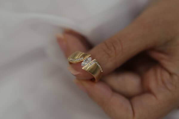 A person holding a Rose Gold Flared Tension Set engagement ring C746 with a diamond in it.