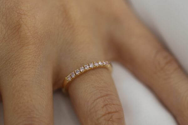 A woman's hand with a luxurious Rose Gold Pink Diamond Wedding Ring C572-Pink adorned in rose gold.